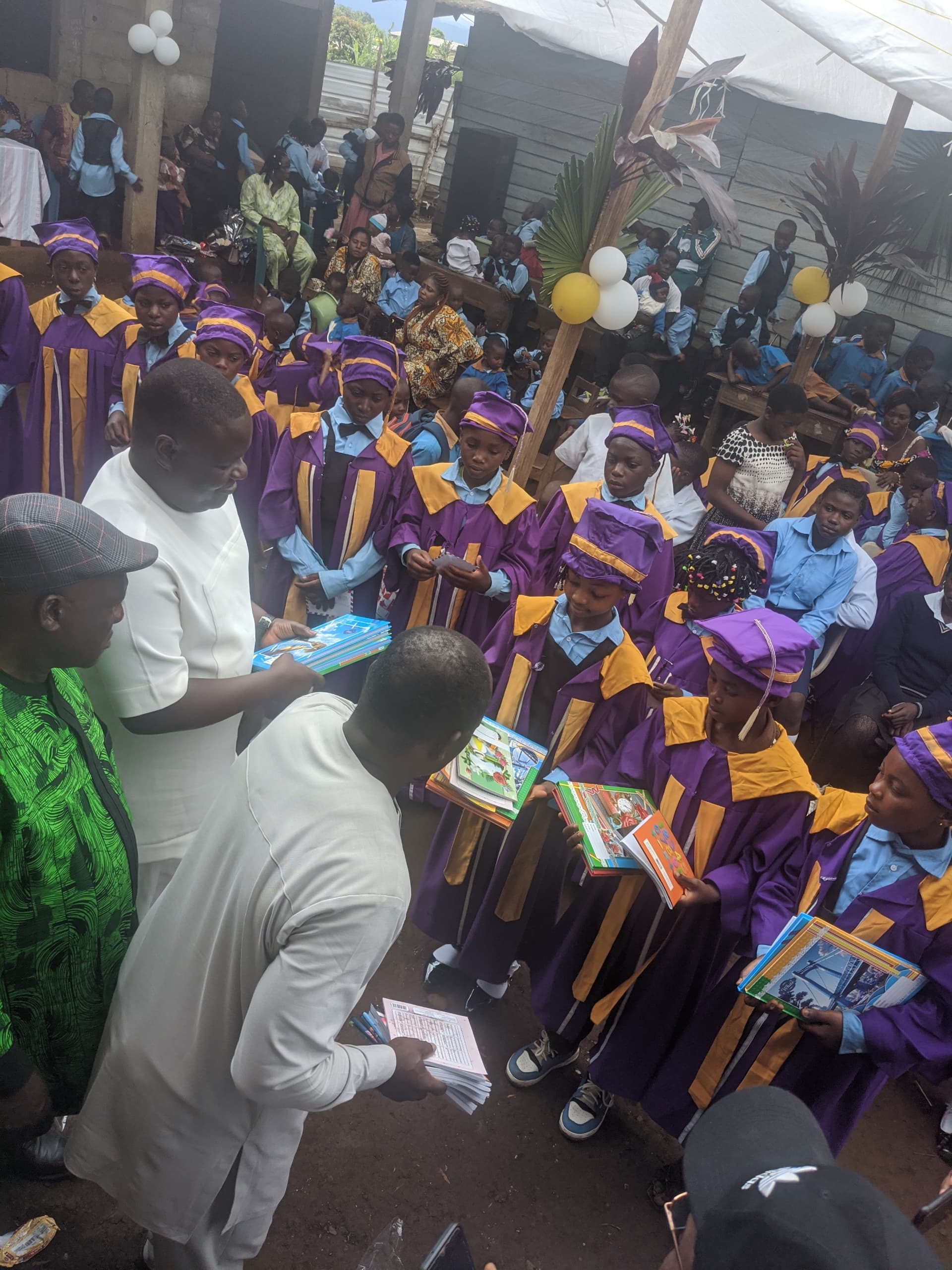 MAMFO representatives handing books to CHIEF pupils in graduation gowns