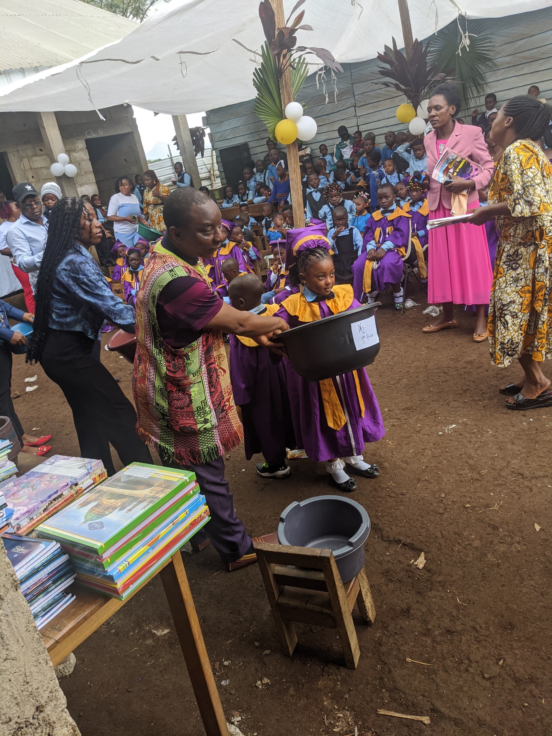Mr Metuge Armstrong presenting a prize to a CHIEF pupil in graduation gown